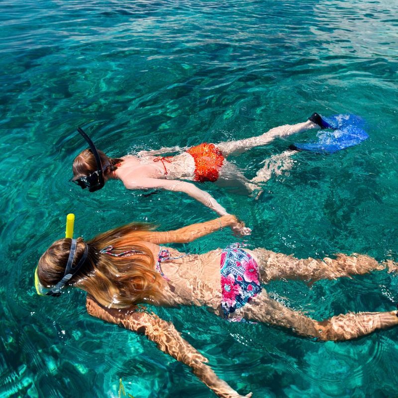 Two women in bikinis are swimming in the ocean.