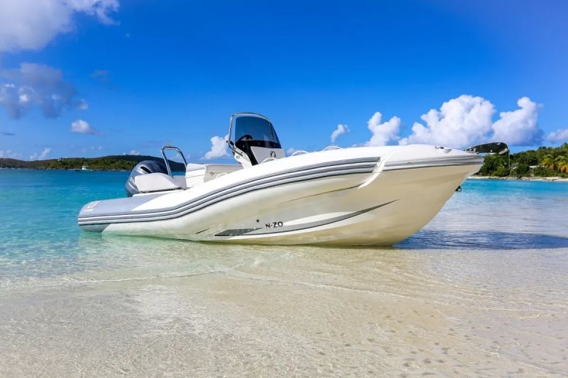 A white boat is sitting on a sandy beach in the ocean.