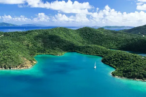 An aerial view of a large body of water surrounded by mountains and trees.