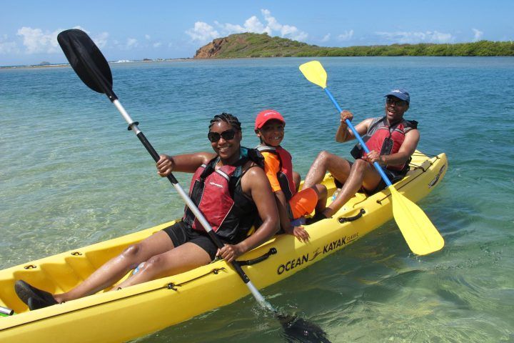 Three people are in a yellow ocean kayak