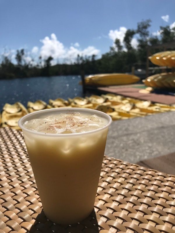 A drink in a plastic cup on a table with kayaks in the background