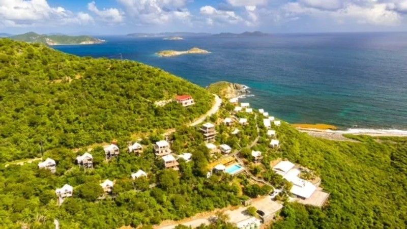 An aerial view of a resort on a hill overlooking the ocean.