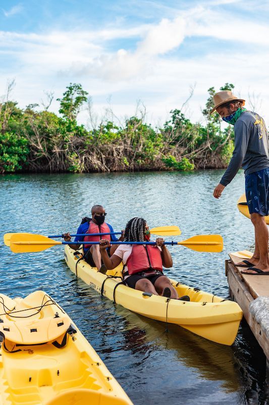 A man is standing on a dock next to two yellow kayaks.