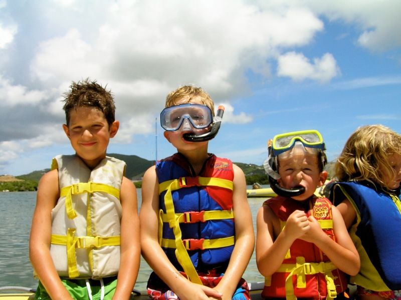 A group of children wearing life jackets and goggles are sitting on a boat