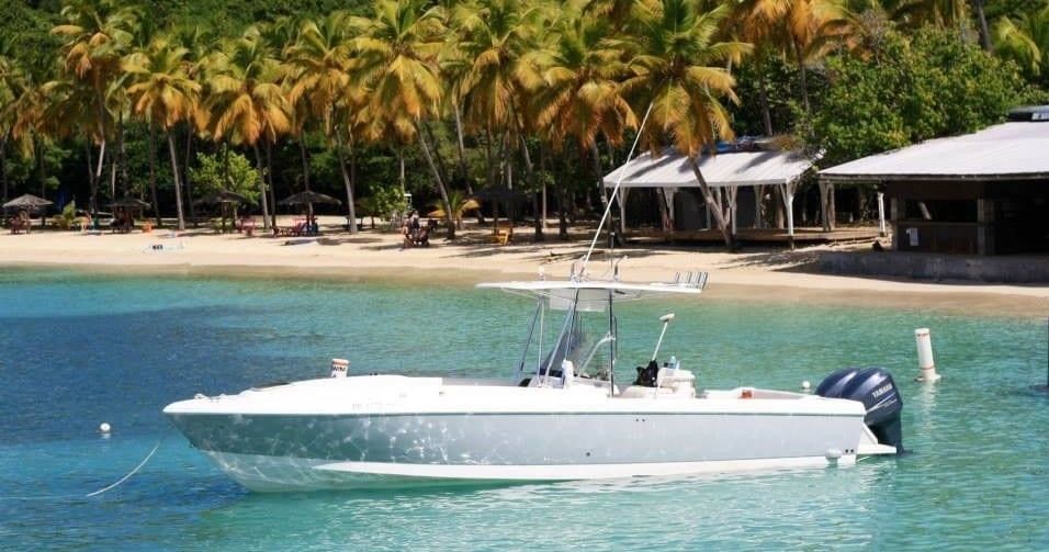 A white boat is floating in the water near a beach