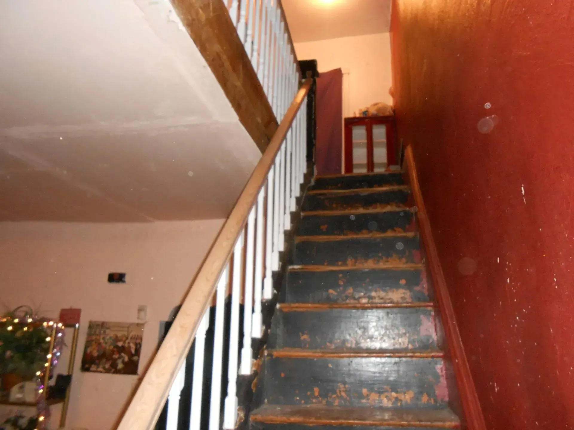 A staircase with a red wall and a white railing