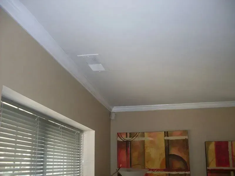 A room with blinds and a painting on the wall