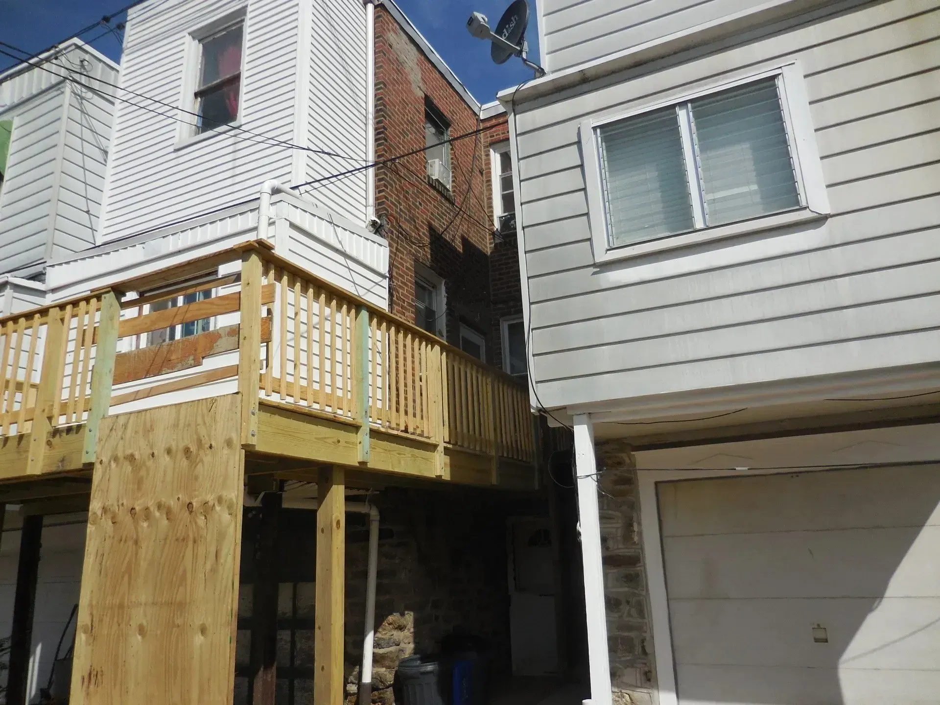 A house with a wooden deck between two other houses