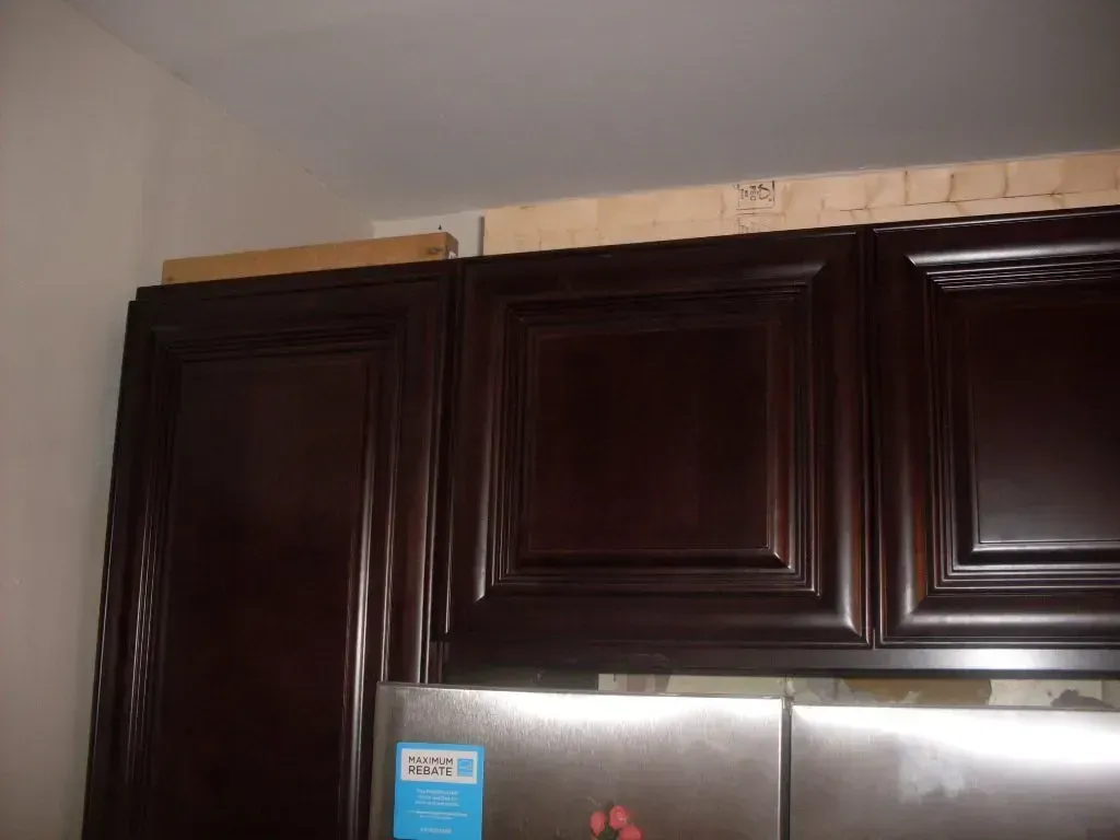 A stainless steel refrigerator in a kitchen with dark wooden cabinets