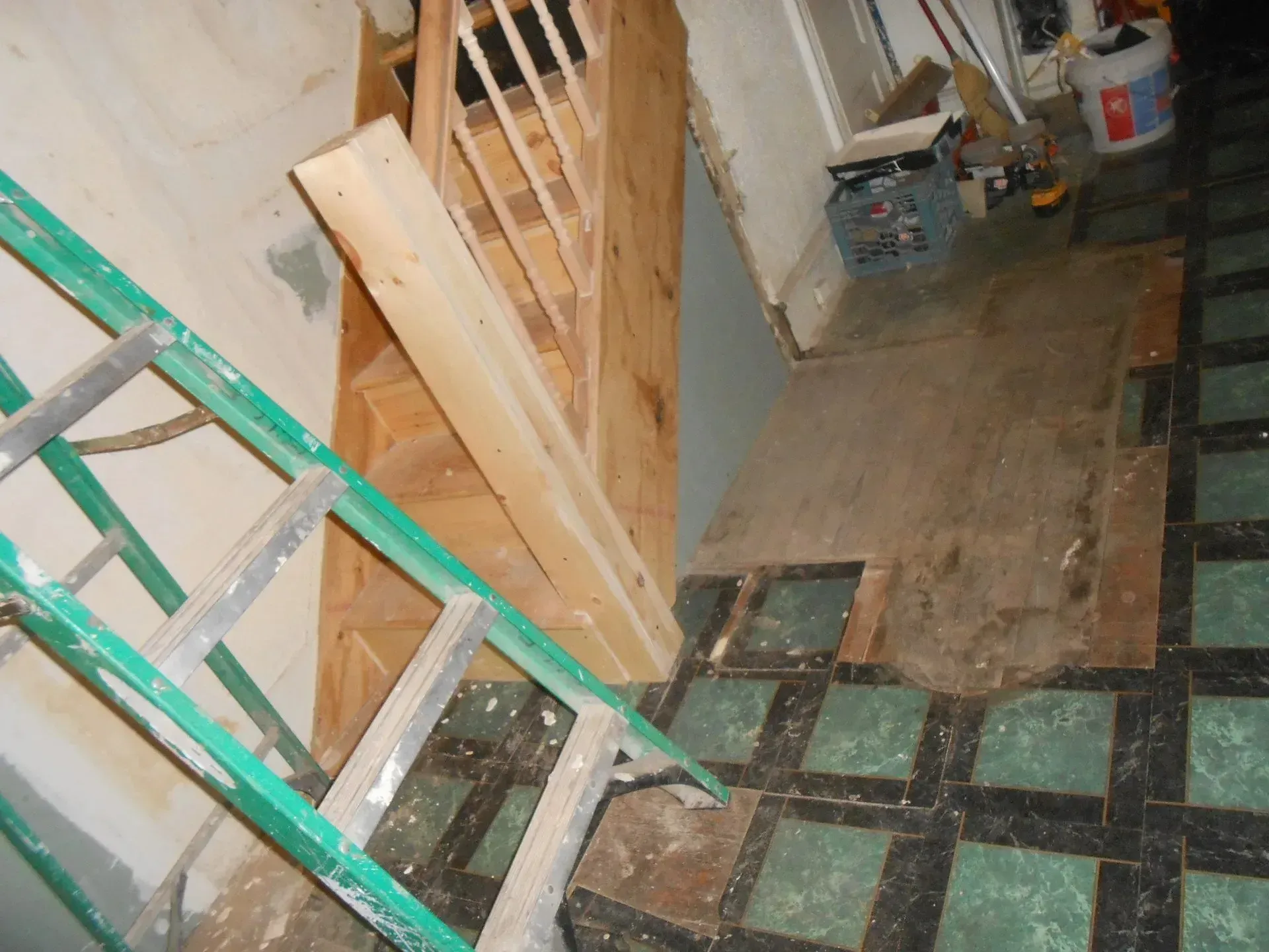 A green ladder is sitting next to a wooden staircase