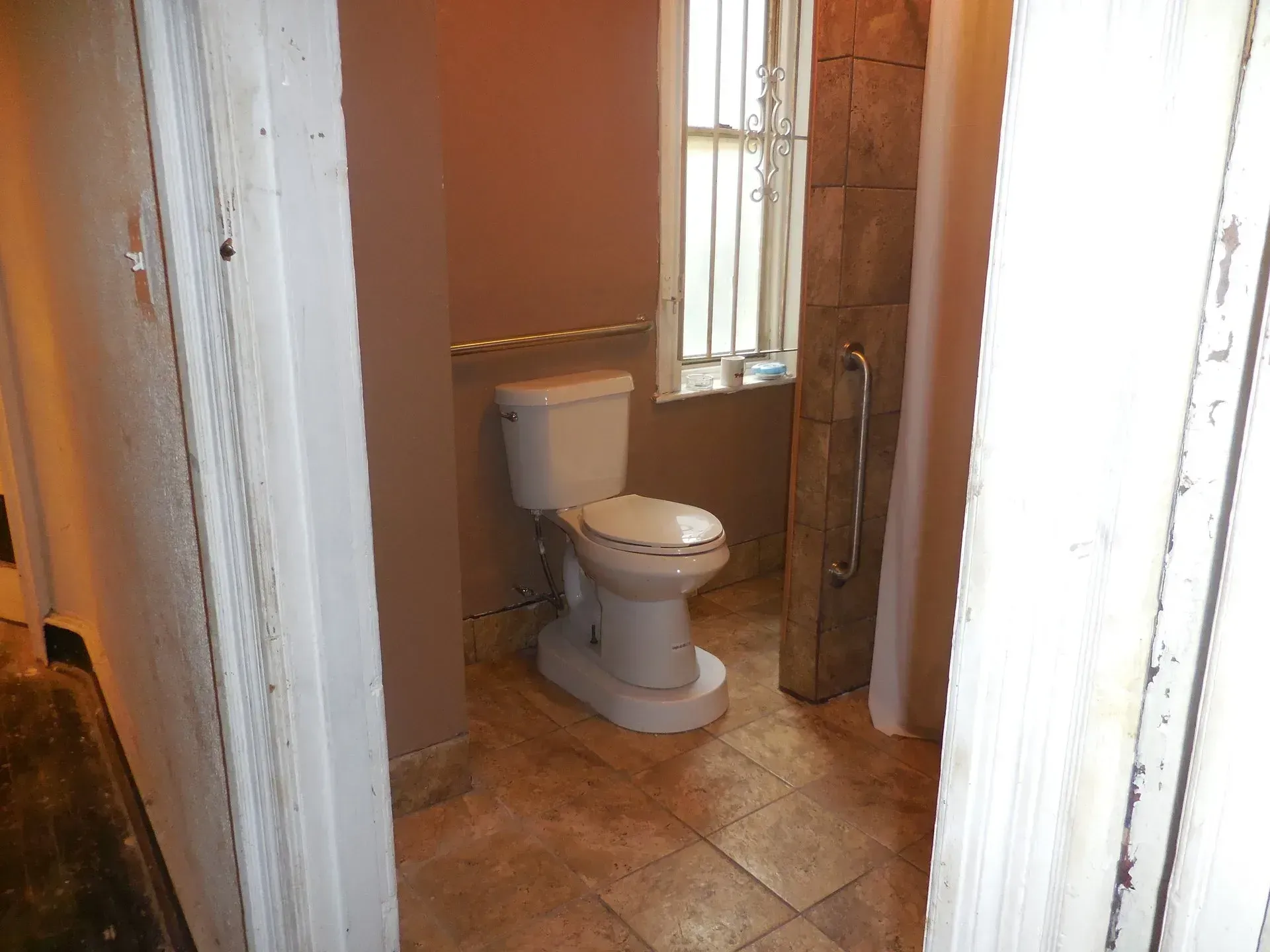 A toilet is sitting in a bathroom next to a window.