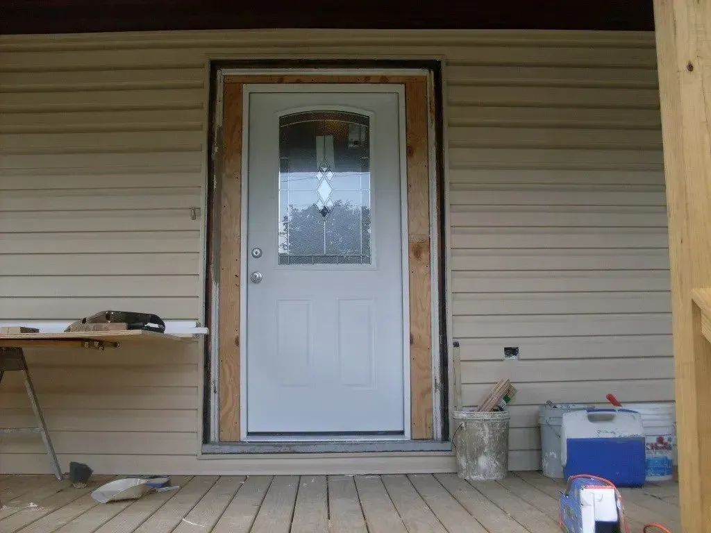 A white door is being installed on a porch