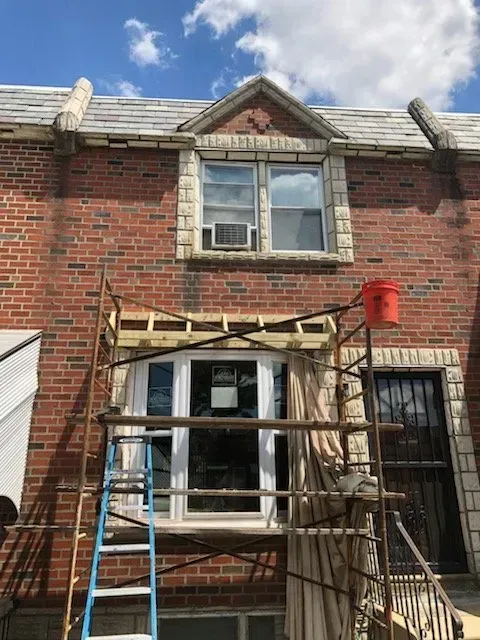 A ladder is sitting on a scaffolding in front of a brick building.