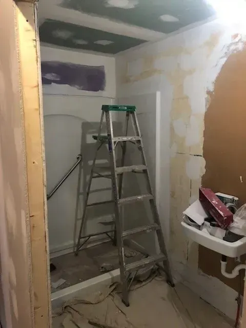 A ladder is sitting in a bathroom next to a sink.