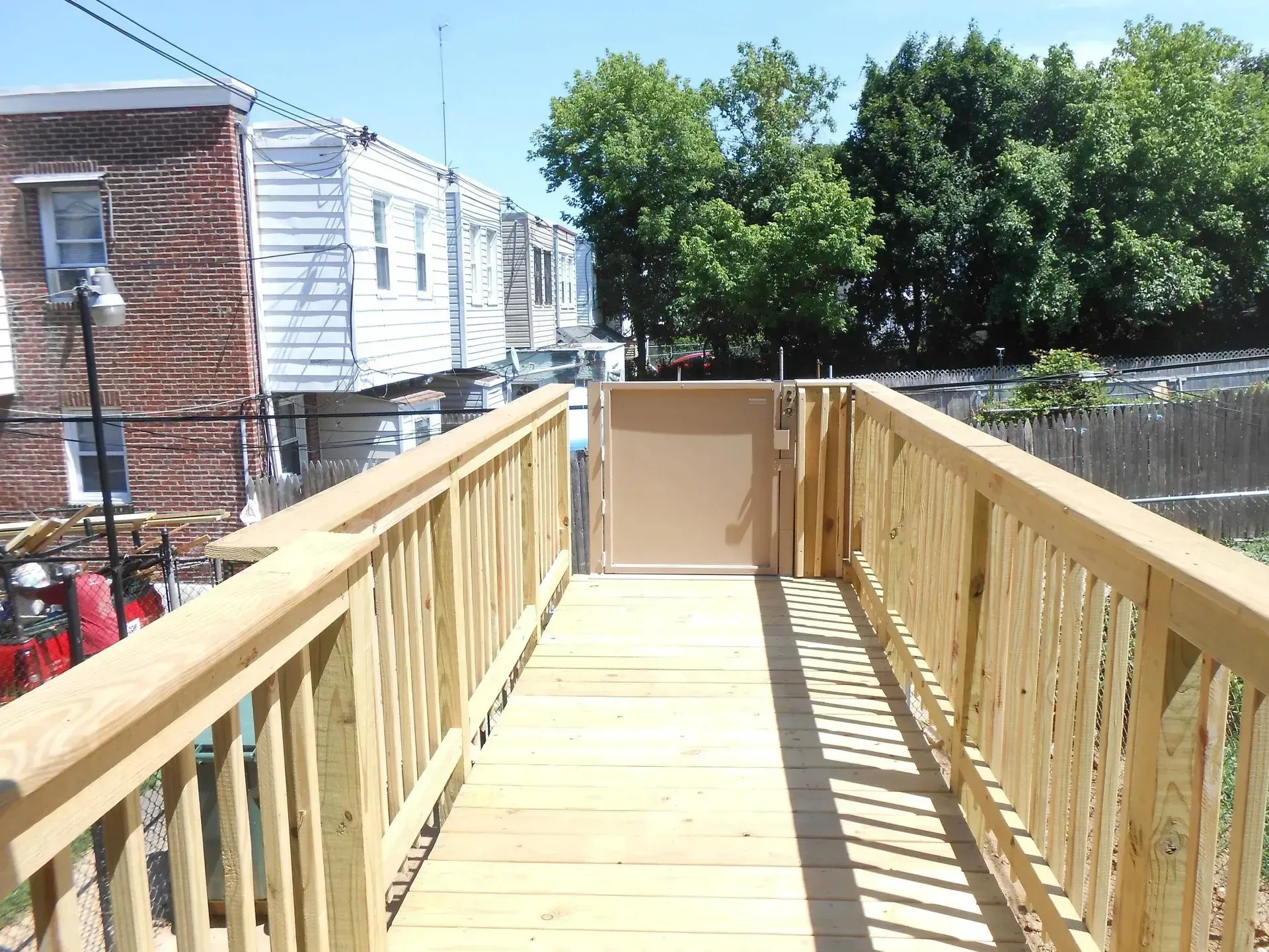 A wooden walkway leading to a fenced in yard