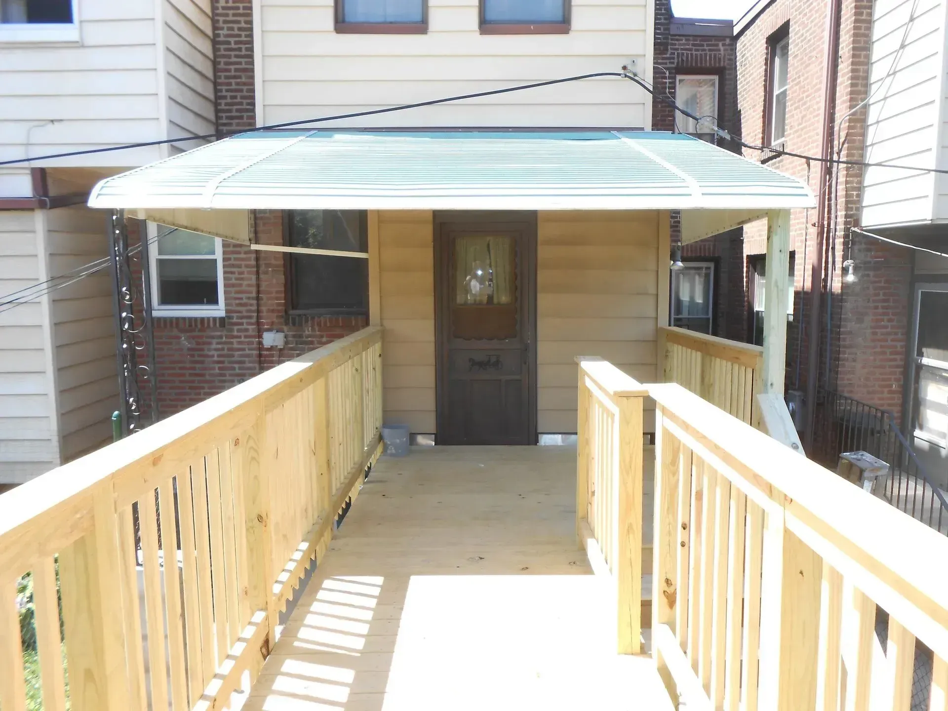 A wooden deck with a canopy over the door of a house
