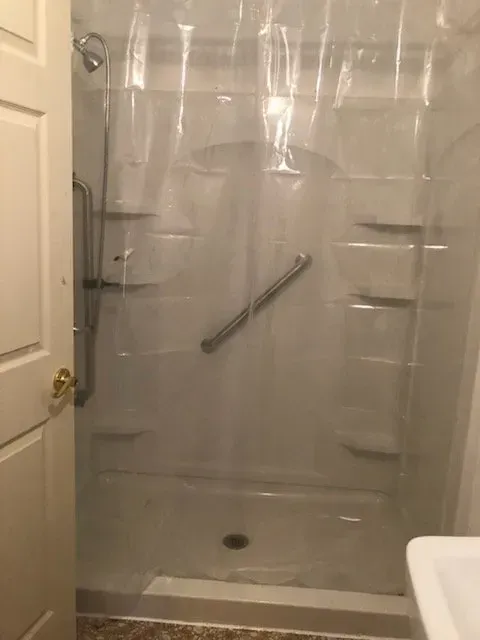 A bathroom with a walk in shower and a clear shower curtain.