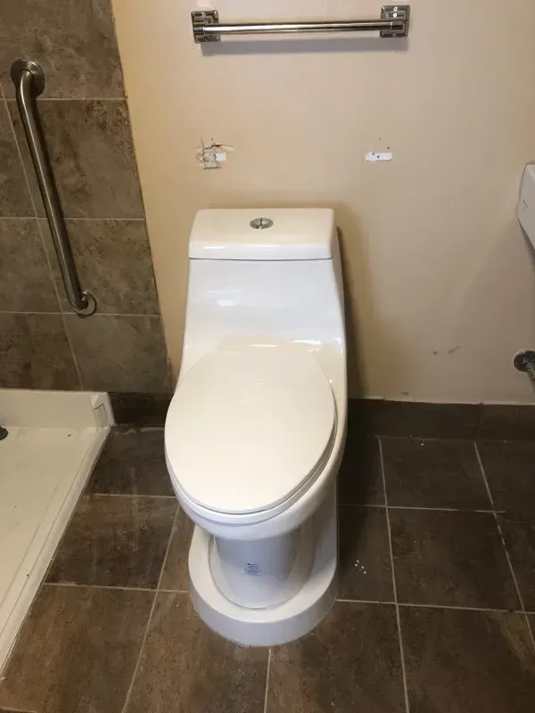 A white toilet is sitting in a bathroom next to a shower.