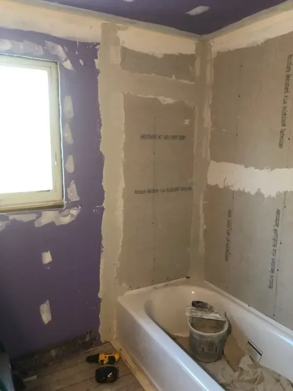 A bathroom under construction with a bathtub and a window.