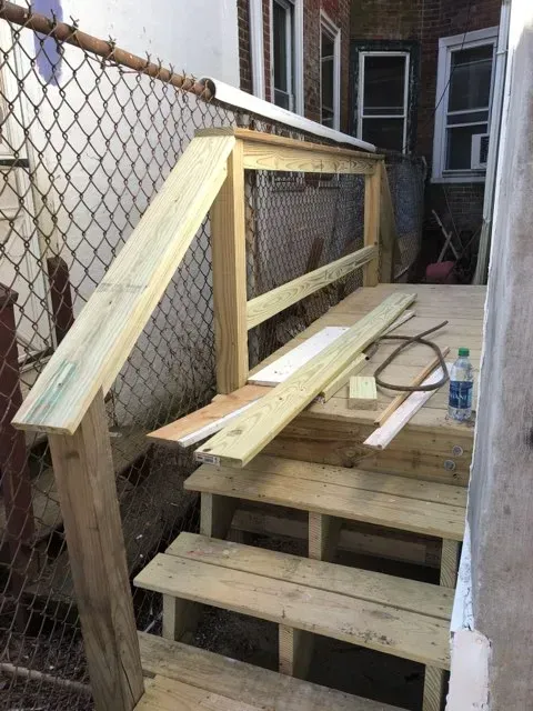 A wooden deck is being built next to a chain link fence.