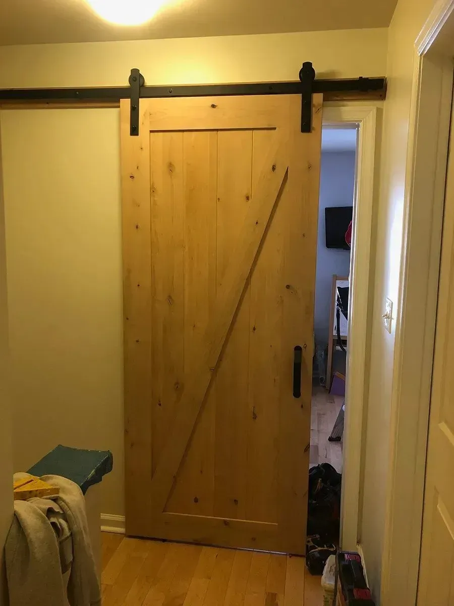 A wooden sliding barn door is in a hallway.