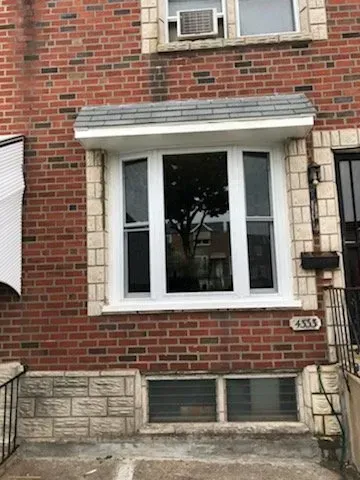 A brick building with a white window and a black door.