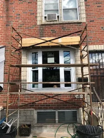 A wooden scaffolding is sitting in front of a brick building.