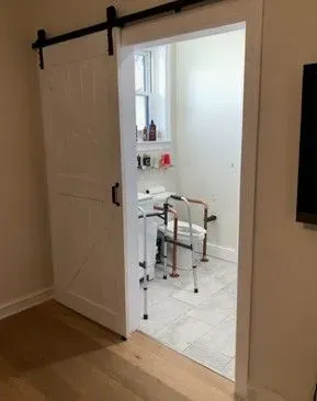 A bathroom with a sliding barn door and a walker.