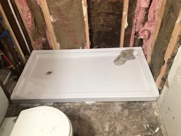 A shower stall is being built in a bathroom next to a toilet.