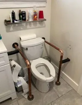 A bathroom with a toilet and a copper railing.