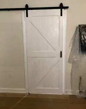 A white sliding barn door with a black railing in a room.