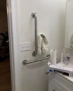A bathroom with a stainless steel hand rail and a towel rack.