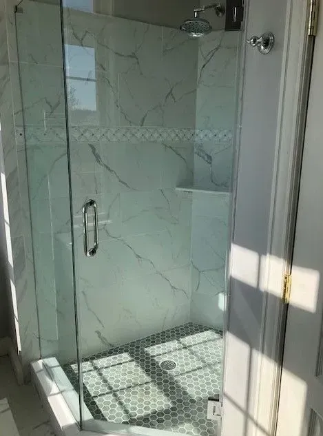 A bathroom with a walk in shower with a glass door.