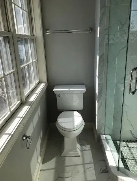 A toilet in a bathroom next to a window