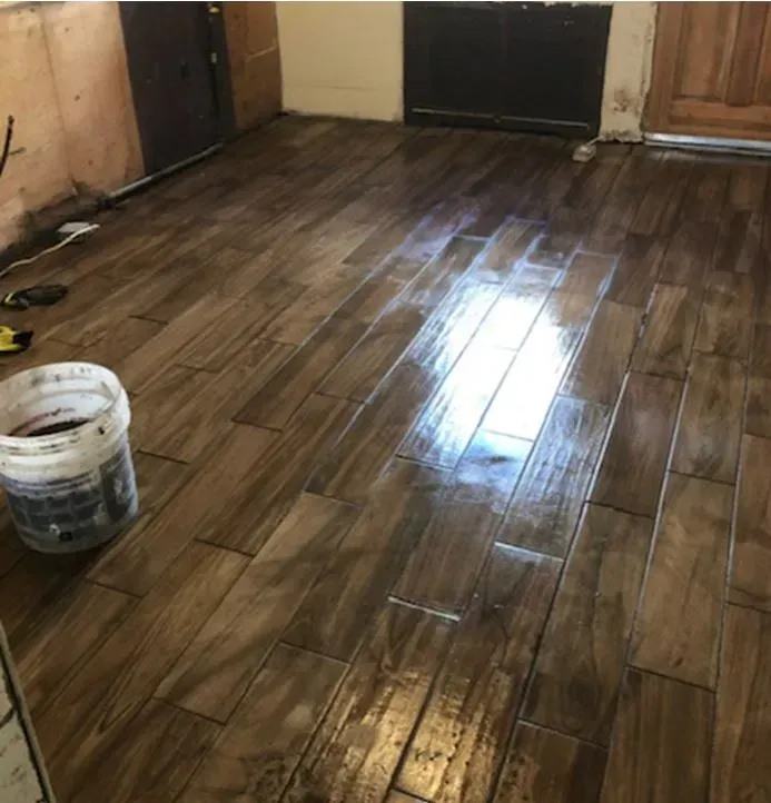 A bucket of paint sits on a wooden floor