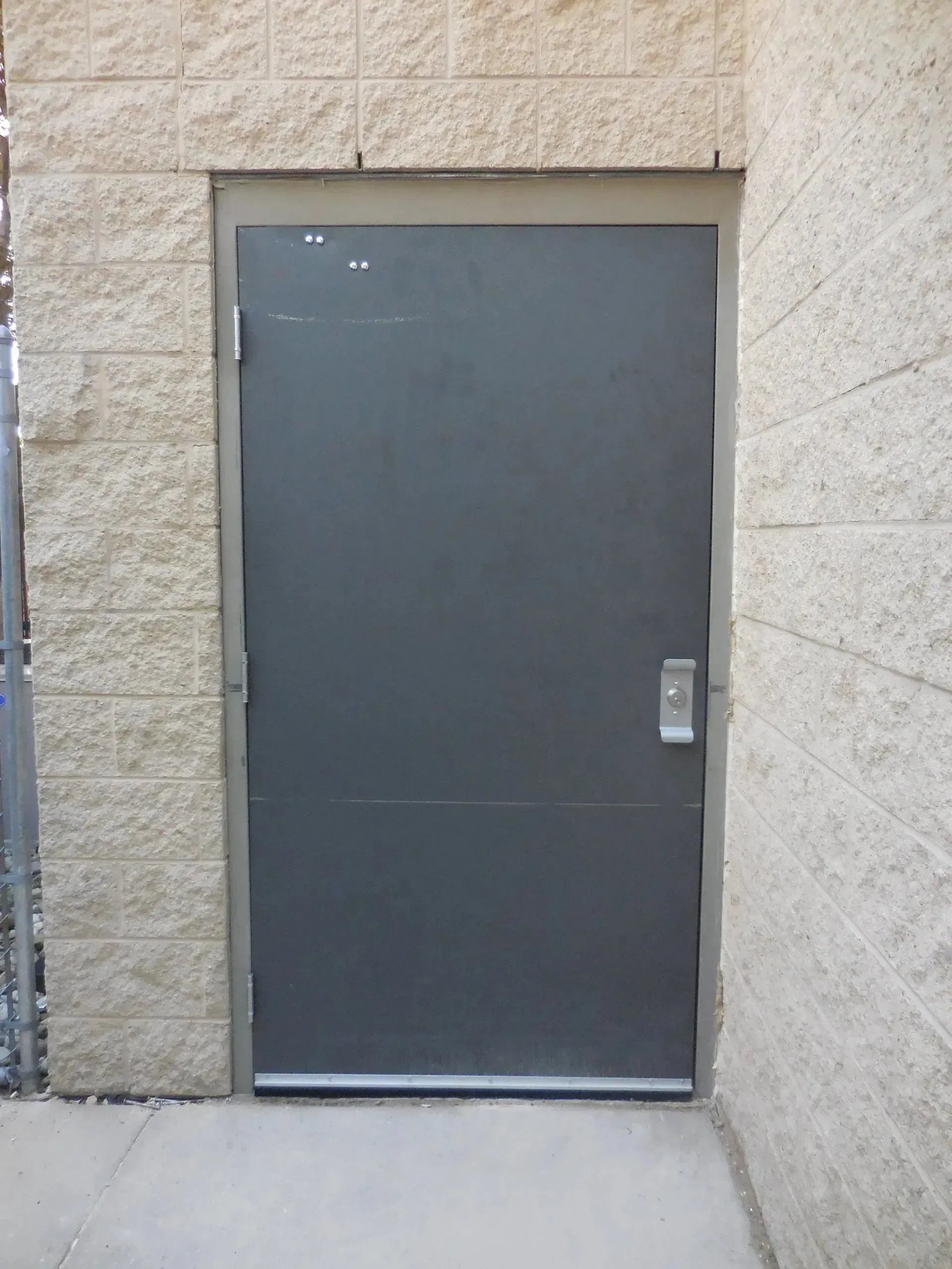 A black door is against a brick wall