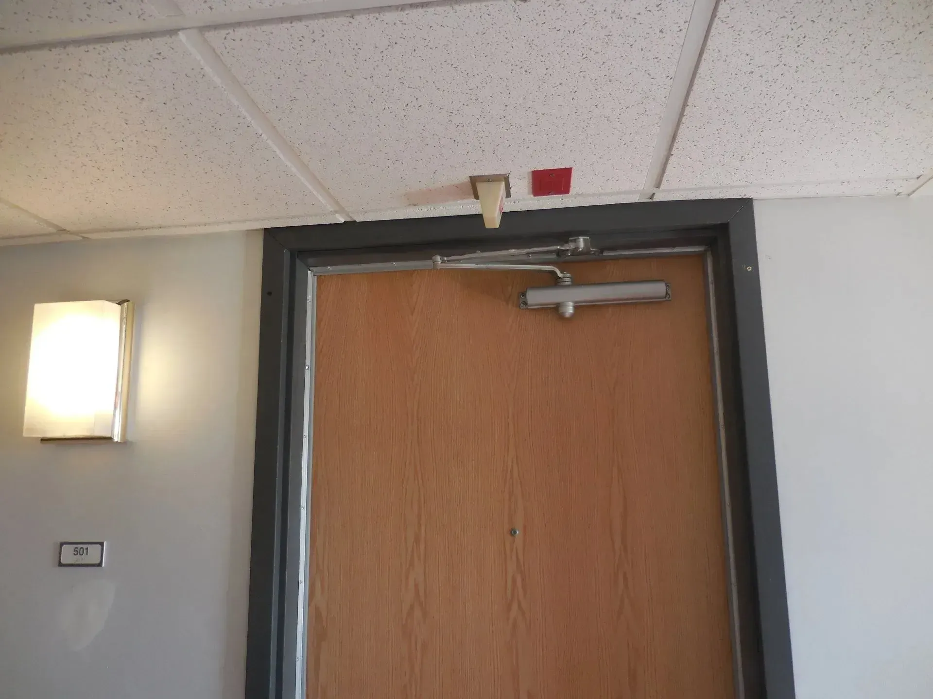 A wooden door with a light on the wall behind it