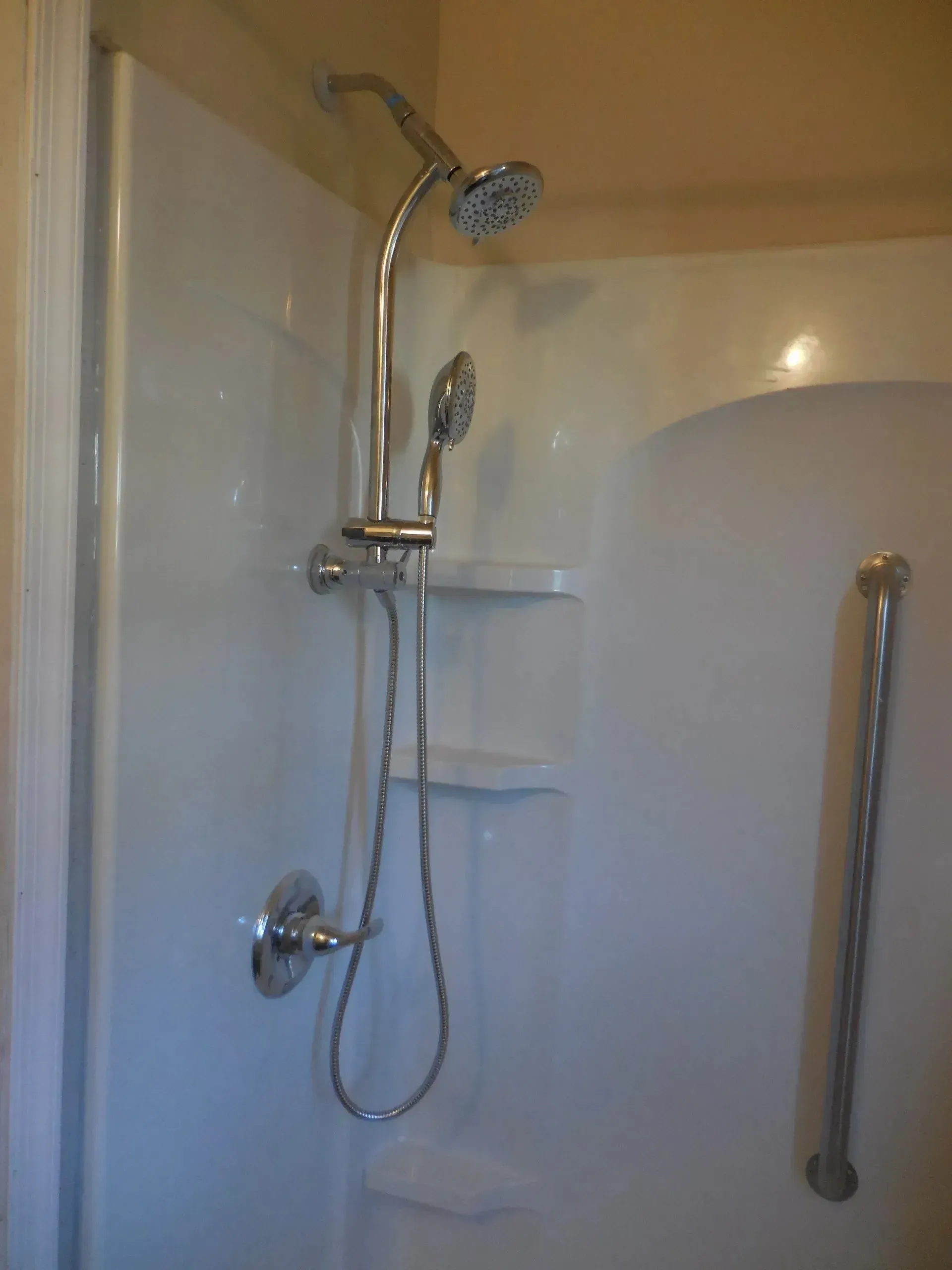 A shower with a hand rail and a shower head.