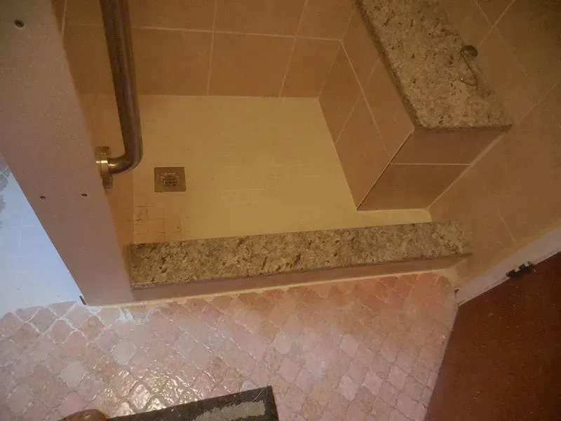 A bathroom with a walk in shower and a granite counter top.