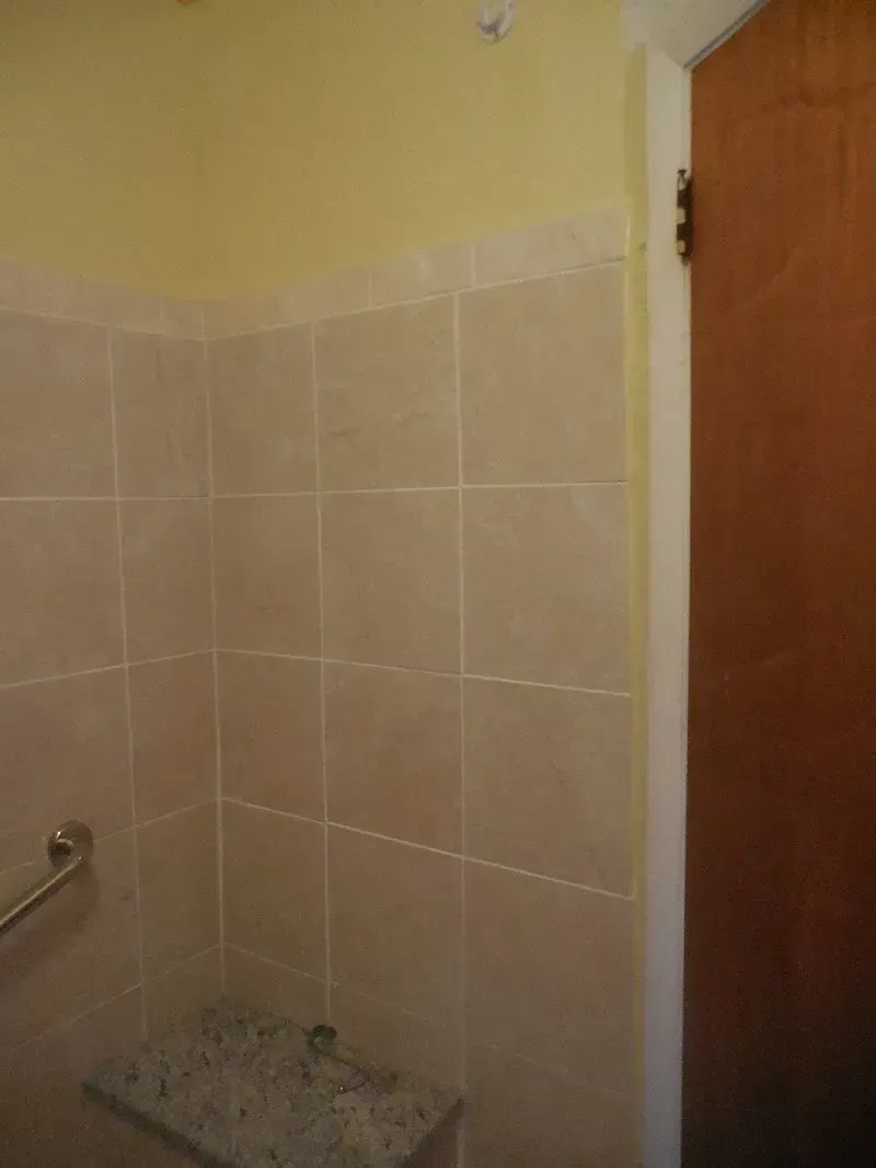 A bathroom with tiled walls and a wooden door.