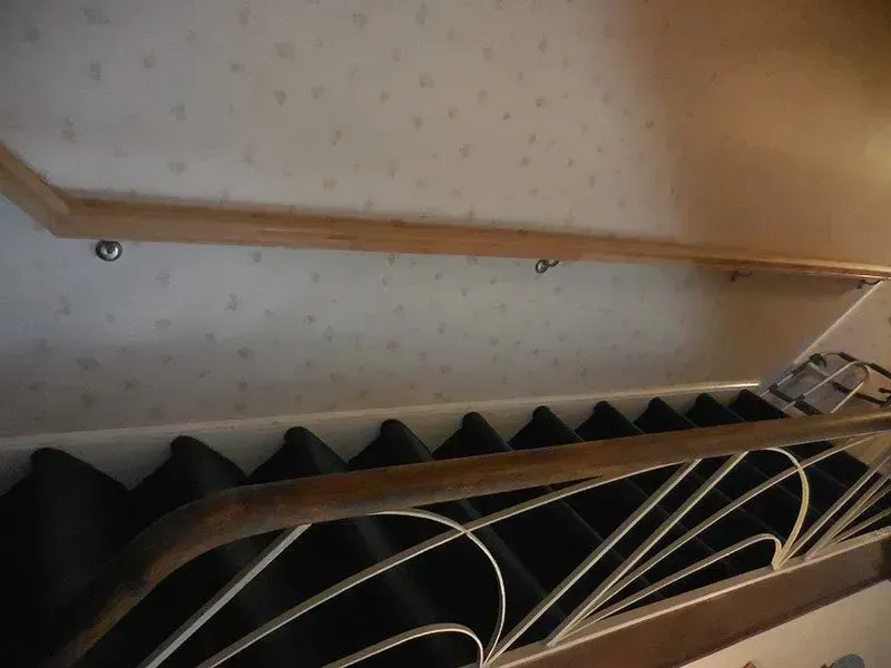 A staircase with a wooden railing and black stairs