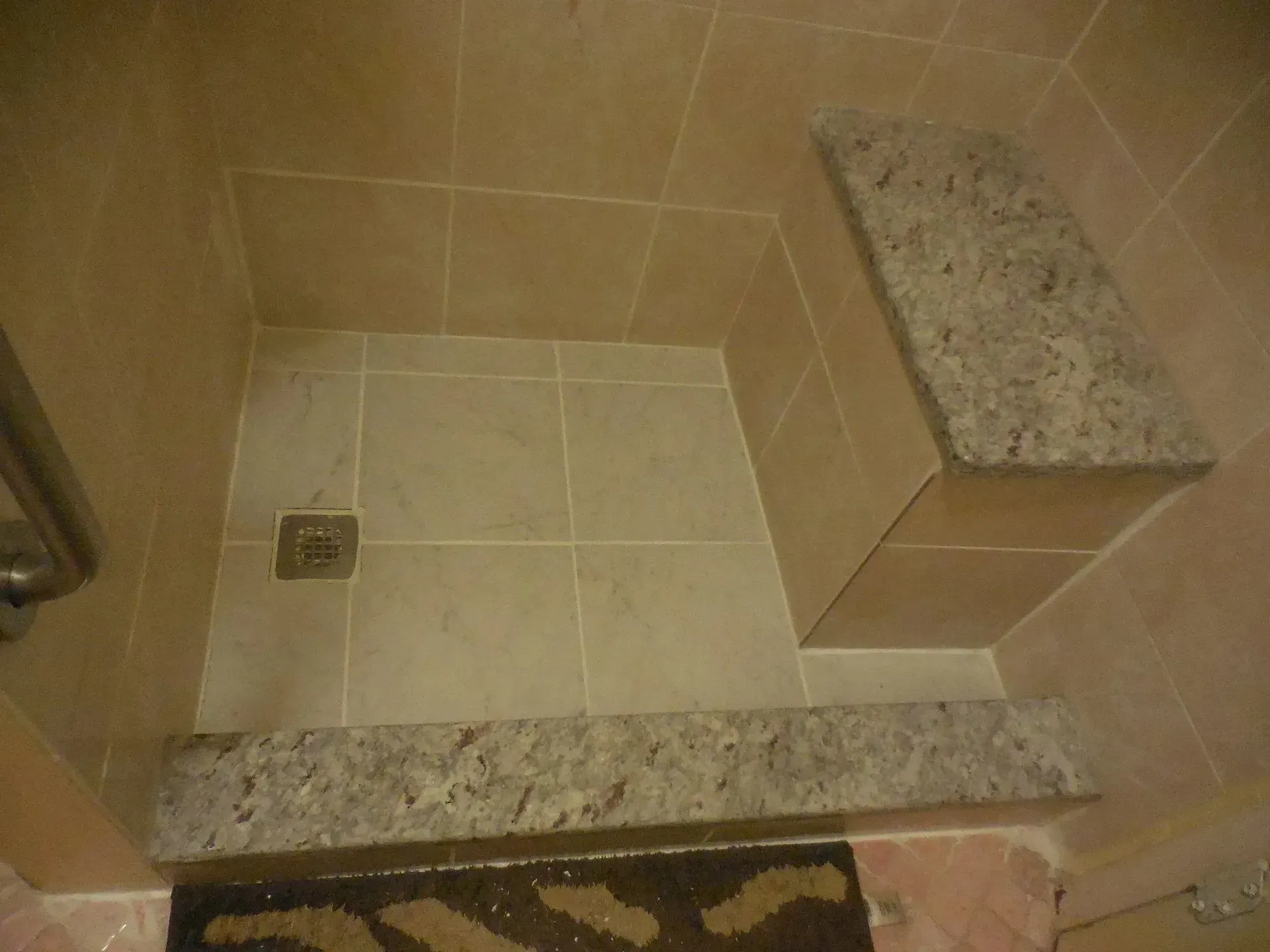 A bathroom with a walk in shower and a bench.