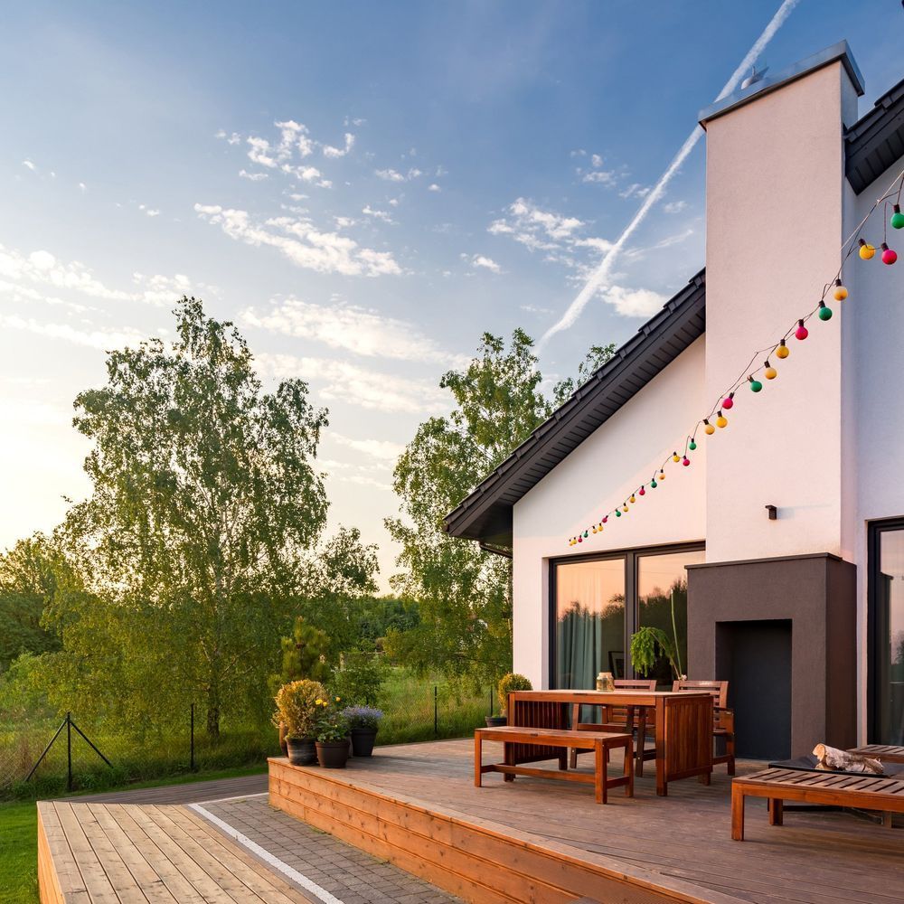 A white house with a wooden deck in front of it.