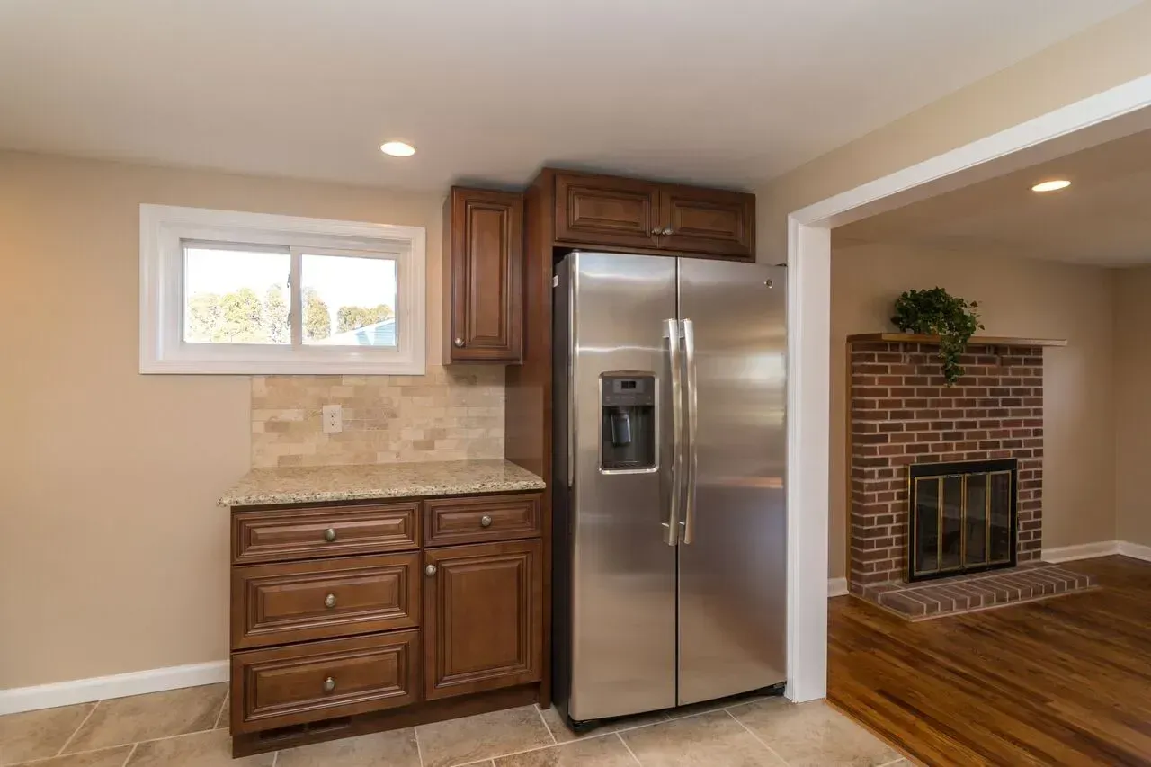 A kitchen with a stainless steel refrigerator and a brick fireplace.