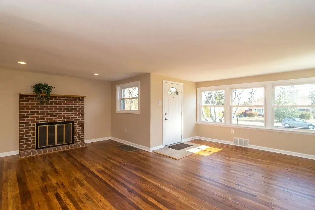 An empty living room with hardwood floors and a fireplace.
