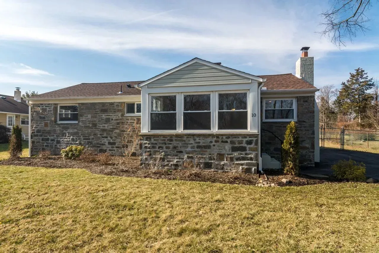 A small stone house with a large lawn in front of it.