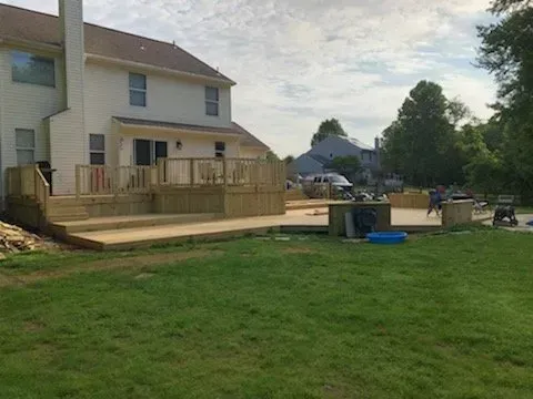 A large wooden deck is being built in the backyard of a house.