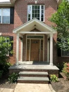 A brick house with a porch and steps leading to the front door.