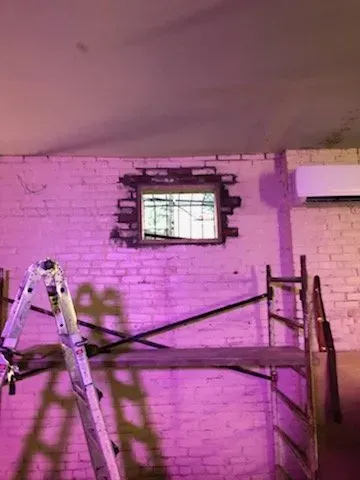 A room with a ladder , scaffolding , and a window.