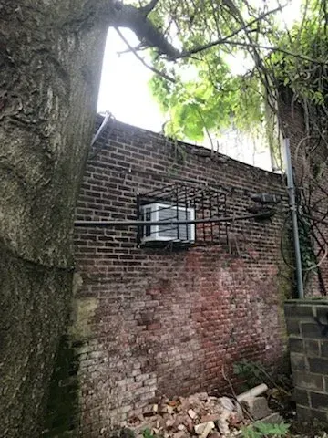 A brick wall with a window and an air conditioner on it.